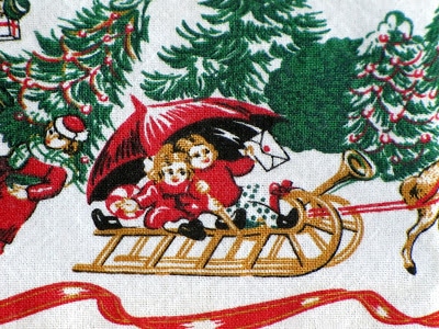 Kids riding a sled on a Christmas tablecloth.