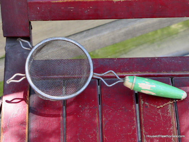 Vintage metal strainer with a green wooden handle.