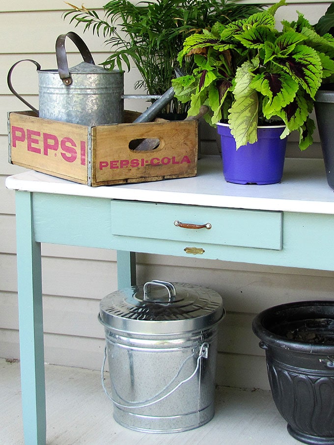 A vintage enamel top table doubles as a potting table or bench.