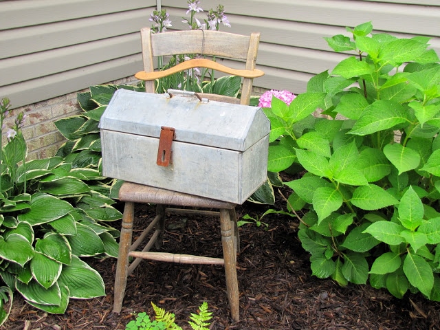 Old metal toolbox setting on a wooden chair.