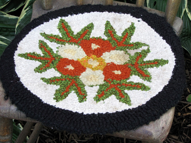 Wool hooked chair pad with a black border.
