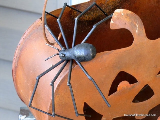 Black spider on a rusty tin pumpkin. 