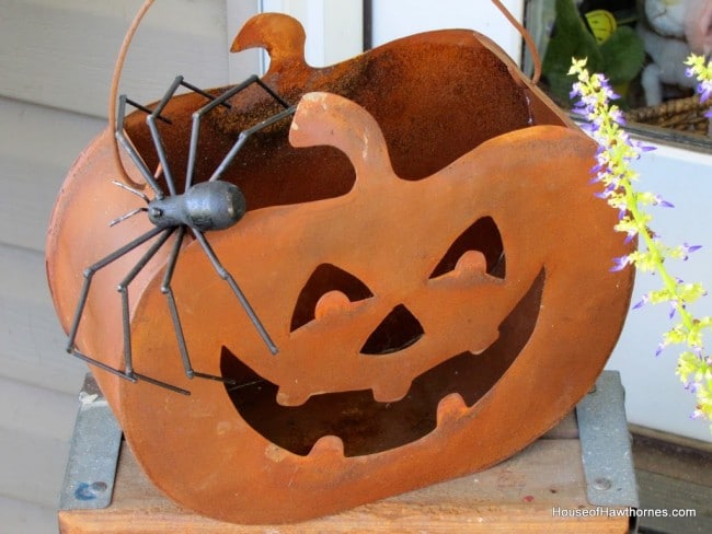 Rusty tin pumpkin used as Halloween porch decor.