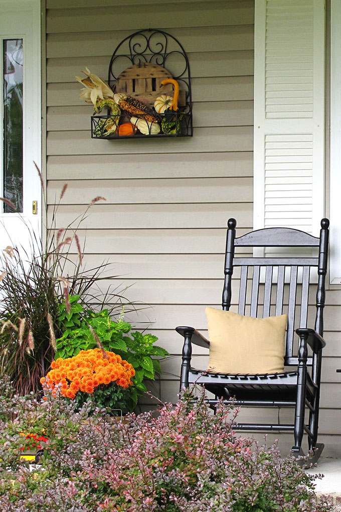 Fun fall front porch decor using traditional cornstalks, Indian corn, gourds and mums along with the unexpected - a vintage toy truck loaded with pumpkins.