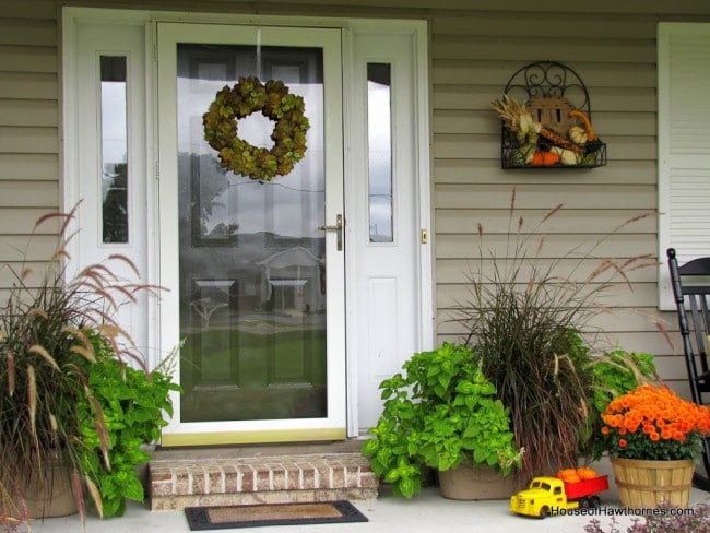 Fun fall front porch decor using traditional cornstalks, Indian corn, gourds and mums along with the unexpected - a vintage toy truck loaded with pumpkins.