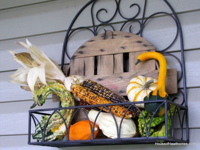 Fun fall front porch decor using traditional cornstalks, Indian corn, gourds and mums along with the unexpected - a vintage toy truck loaded with pumpkins.