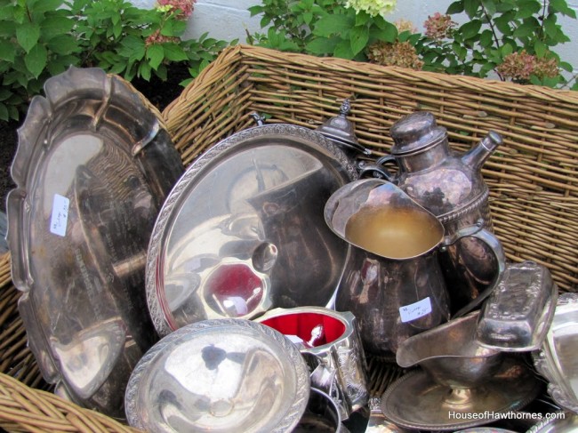Basket full of silver plated serving places and tea sets.