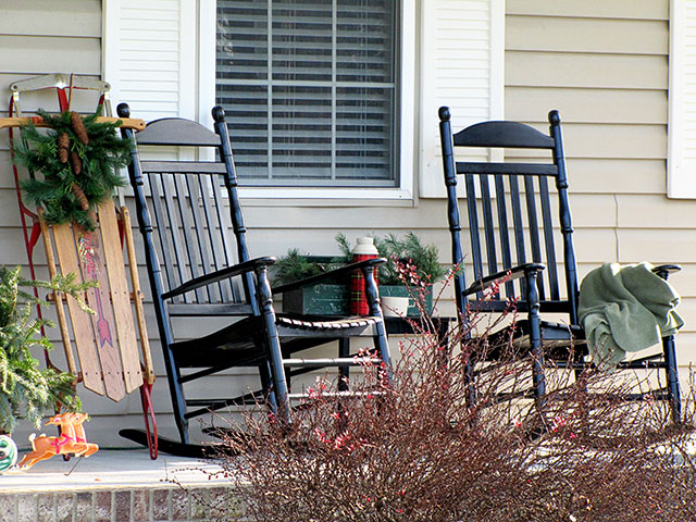 Black rockers and vintage sled on a winter front porch.