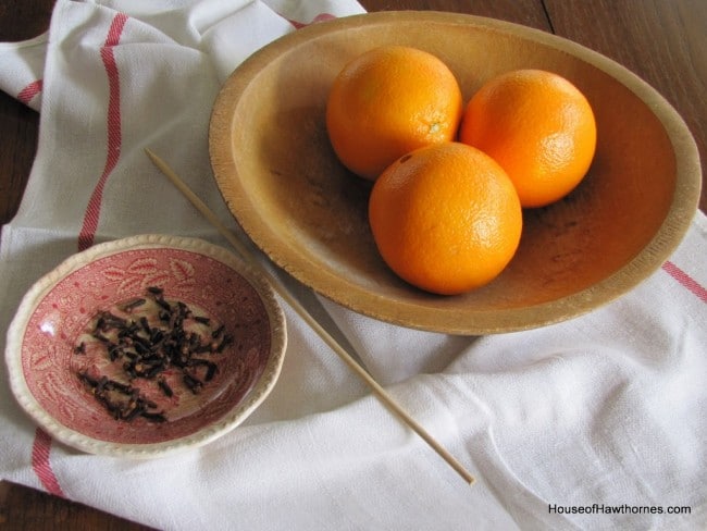 Supplies to make orange pomanders - cloves, oranges and wooden skewer.