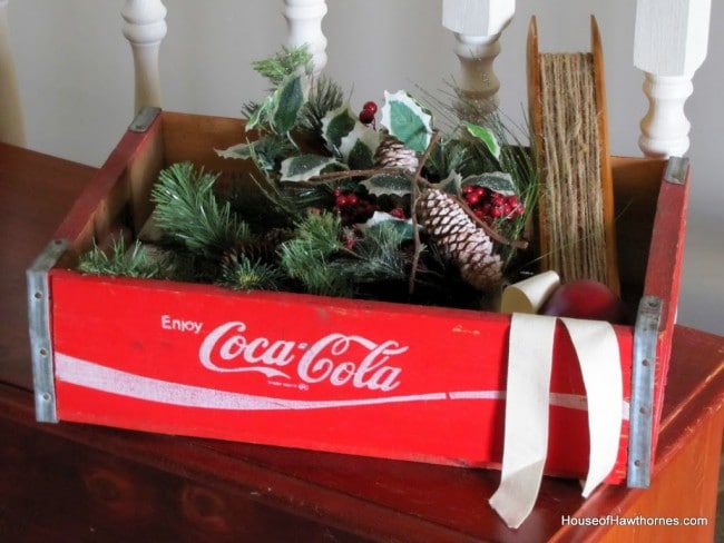 Bright red Coca-Cola crate with Christmas greenery in it.