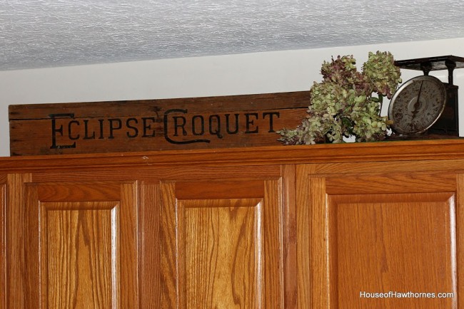 Old croquet box setting on top of kitchen cabinets.
