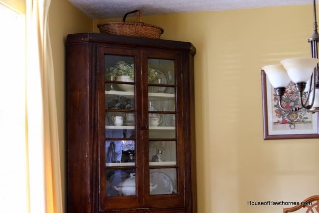 Corner cupboard with basket on top.