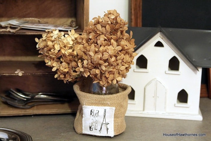 Dried hydrangeas displayed in a burlap vase. 