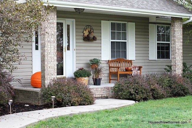 Fall front porch ideas including a HUGE pumpkin, apples, gourds and lots of autumn flowers and perennials.