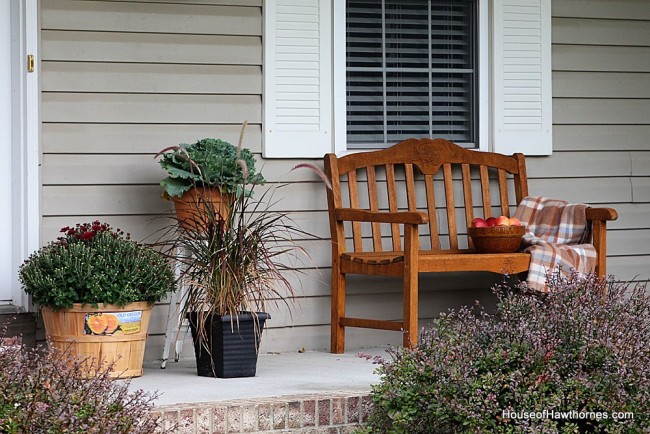 Fall front porch ideas including a HUGE pumpkin, apples, gourds and lots of autumn flowers and perennials.