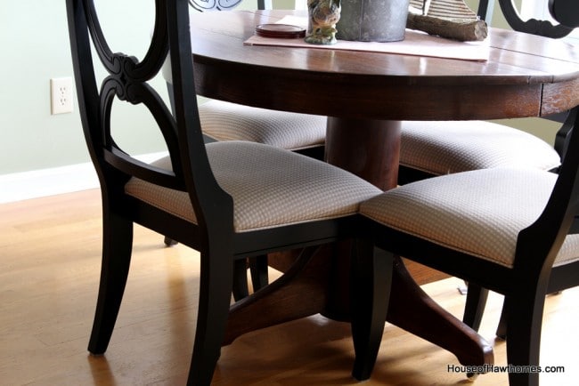 Black chairs with an oak pedestal table.