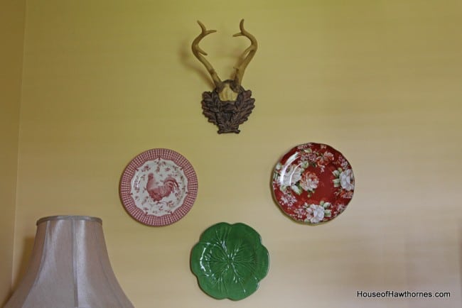 China plates mounted to the wall along with deer antlers.