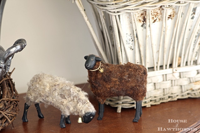 Two fuzzy decorative lambs setting on a table. 