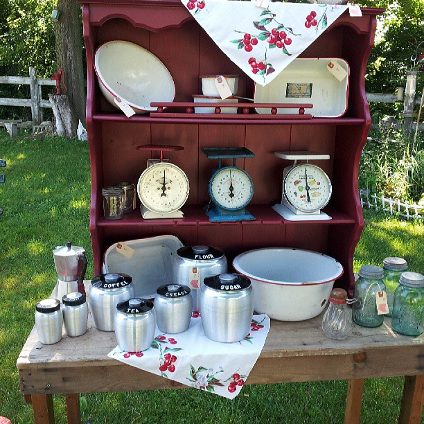 Vintage kitchen scales and aluminum canister set sitting on a red hutch.