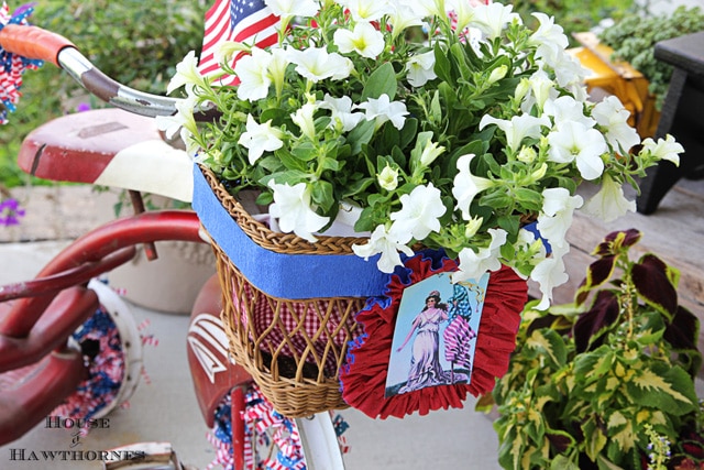 A vintage little red Tricycle decorated for the 4th of July with patriotic crepe papers, flags and flowers. A cute DIY project for patriotic porch decor. 