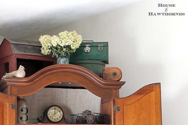 A farmhouse look on top of a cabinet including a red toy barn and some toolboxes.