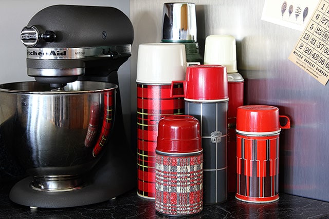 Collection of vintage thermoses used as kitchen decor 