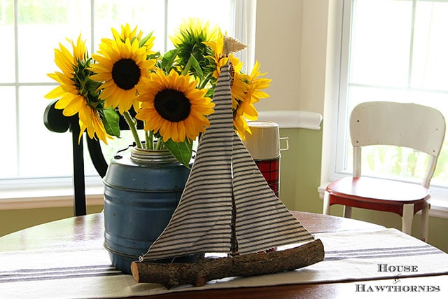 Sunflower vignette using vintage picnic jug, thermoses and twig sailboat