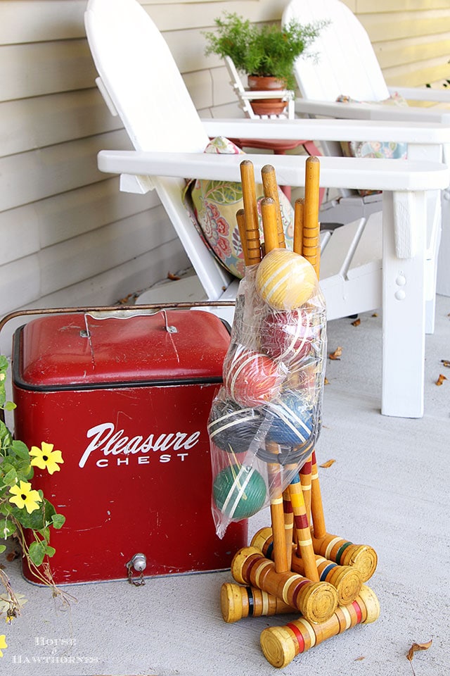 Vintage croquet set wrapped up from the thrift store and red Pleasure Chest cooler sitting on the porch.