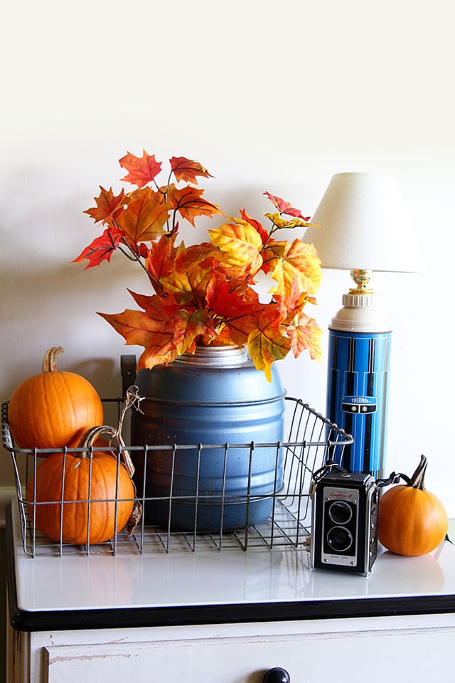 Easy fall vignette with a vintage Thermos jug, dollar store leaf stems and pumpkins.  via houseofhawthornes.com