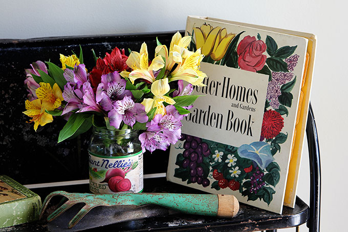 Vintage style garden decorating in the entryway, including vintage garden planters, gardening tools and colorful retro Better Homes and Gardens Garden Book.