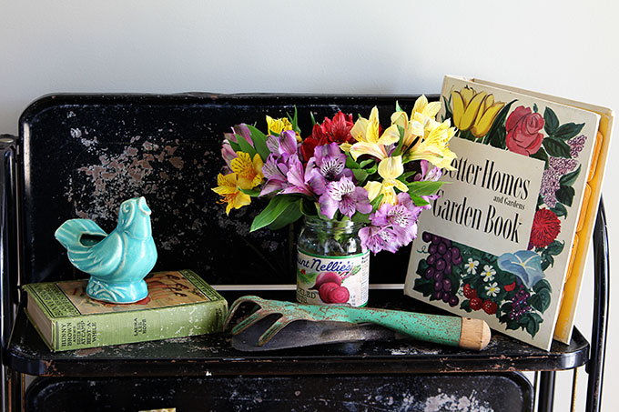 Vintage style garden decorating in the entryway, including vintage garden planters, gardening tools and colorful retro Better Homes and Gardens Garden Book.