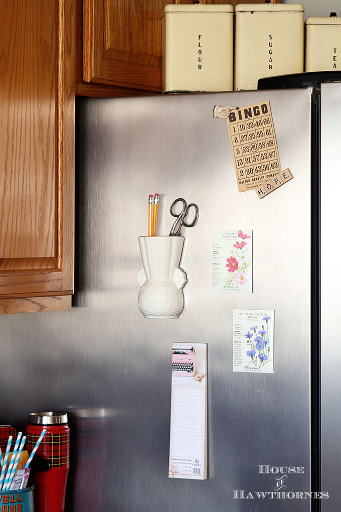 The side of the refrigerator with seed packets and a vintage wall packet attached.