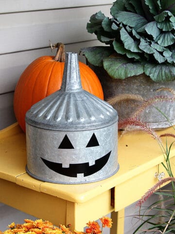 A super cute repurposed Jack-o'-Lantern for Halloween made from a galvanized funnel. A quick and easy DIY project for fall!