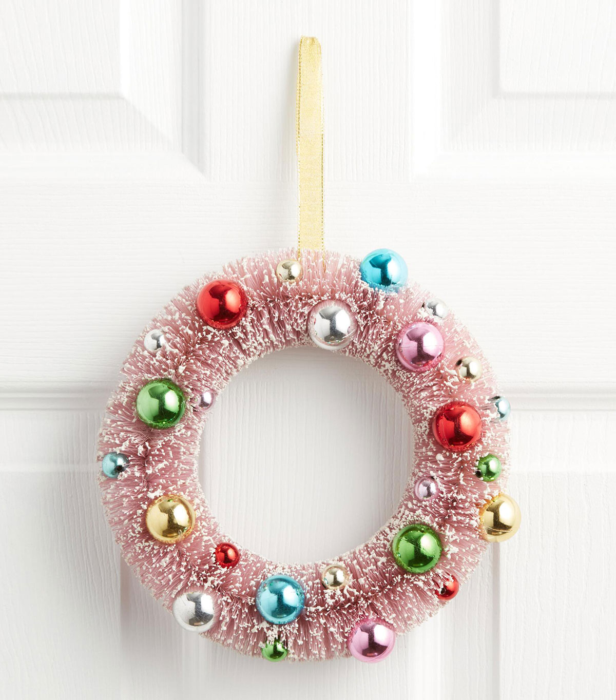 Pink bottle brush wreath with tiny ornaments on it.