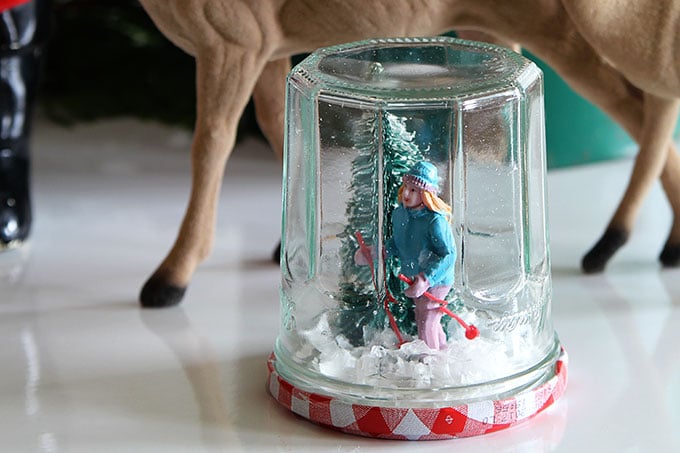 Learn how to make a super cute DIY snow globe from a jelly jar. A quick, easy and inexpensive holiday craft project the kids can help with.