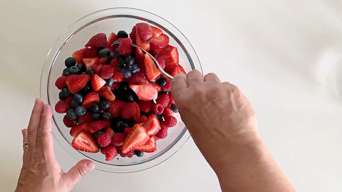 Mixing berries in a glass mixing bowl.