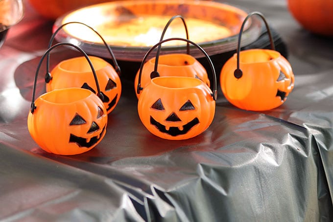 Plastic Halloween pumpkin candy containers at a traditional Halloween party with orange and black decor including blow molds and vintage inspired Halloween decorations.