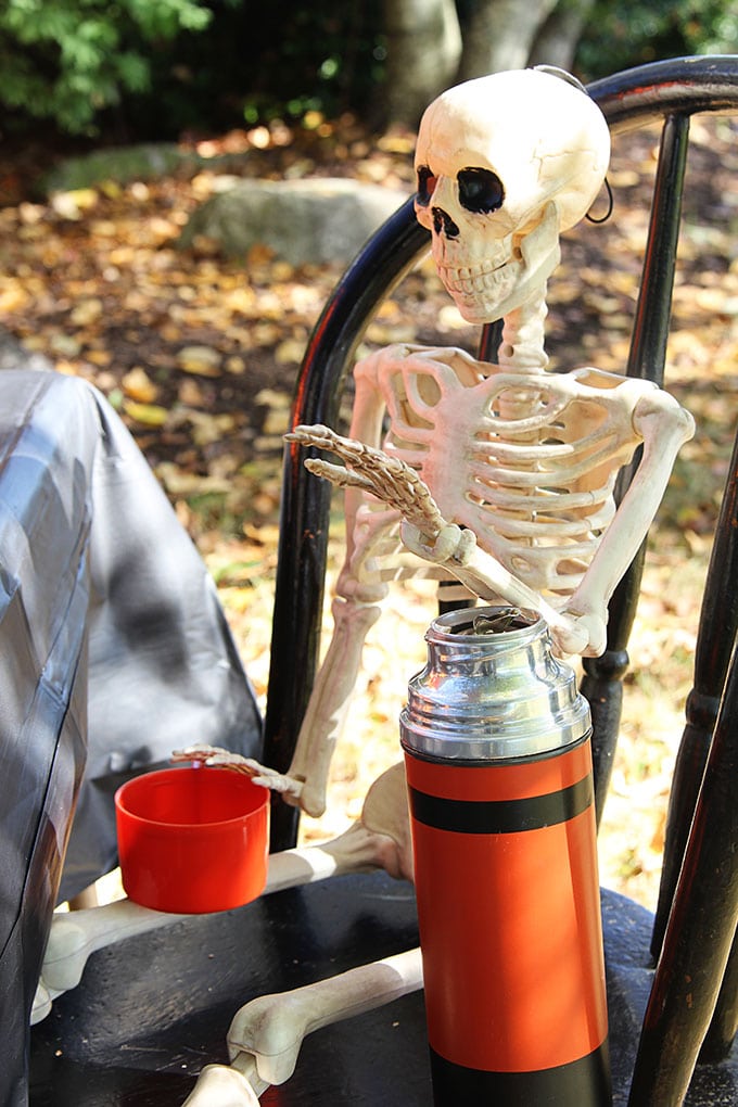 Skeleton at a traditional Halloween party with orange and black decor including blow molds and vintage inspired Halloween decorations.