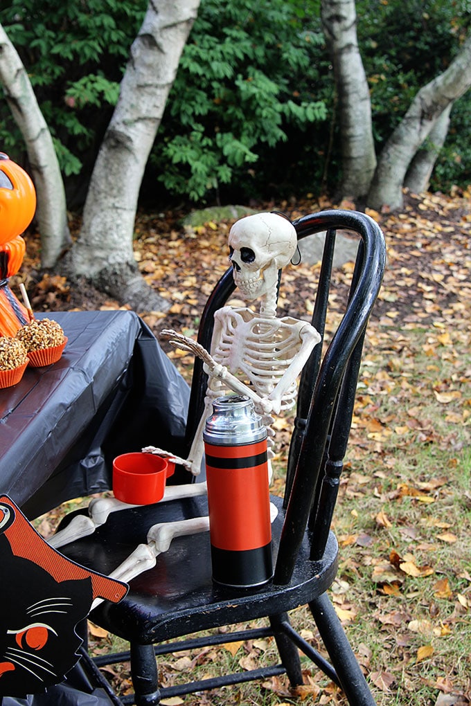 Skeleton at a traditional Halloween party with orange and black decor including blow molds and vintage inspired Halloween decorations.