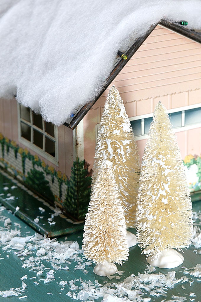 A mid-century modern Christmas dollhouse complete with a tiny little tinsel Christmas tree and Santa on the rooftop.