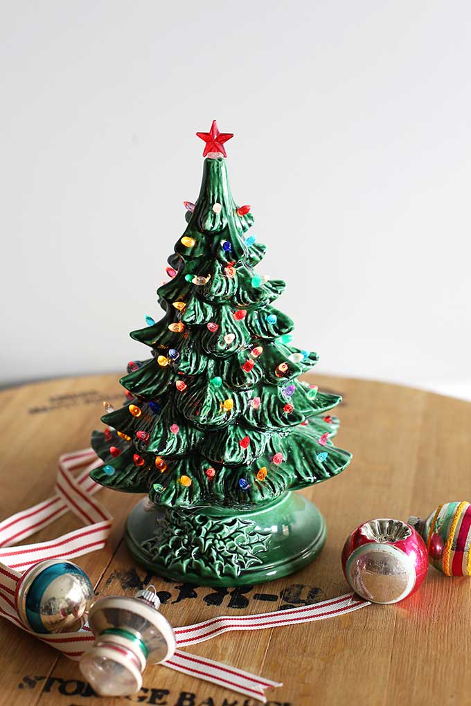 Green vintage ceramic Christmas tree with colored lights.