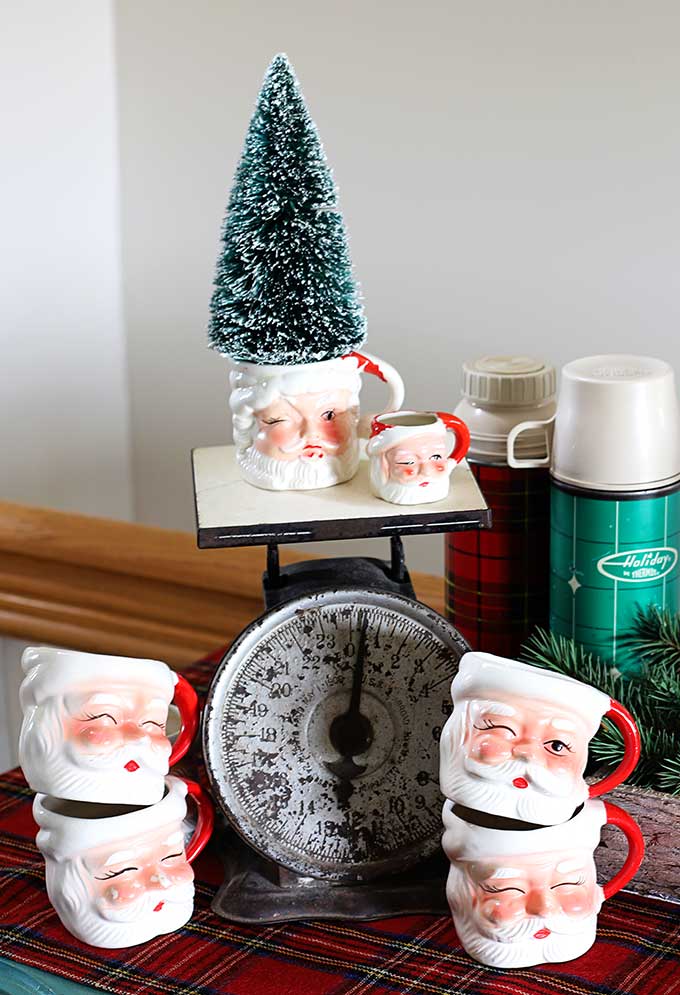 Vintage Santa mugs setting on a vintage kitchen scale. 