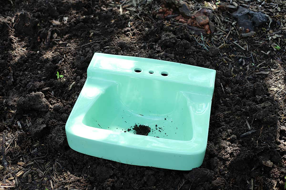 vintage porcelain bathroom sink dug into ground