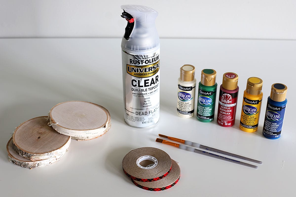 supplies needed for making coasters - wood slices, craft paint, paint brushes, sealer and tape