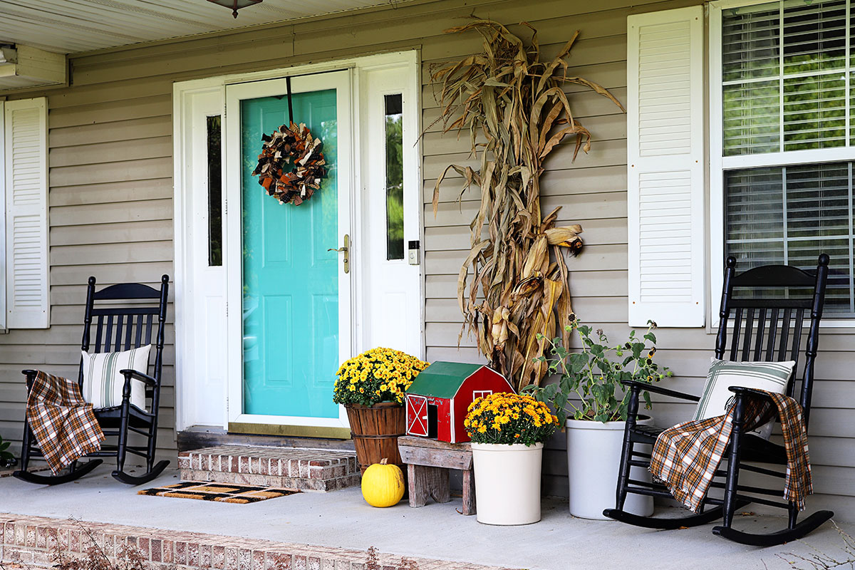 Front porch decorated in a farmhouse style with a small folk art barn.