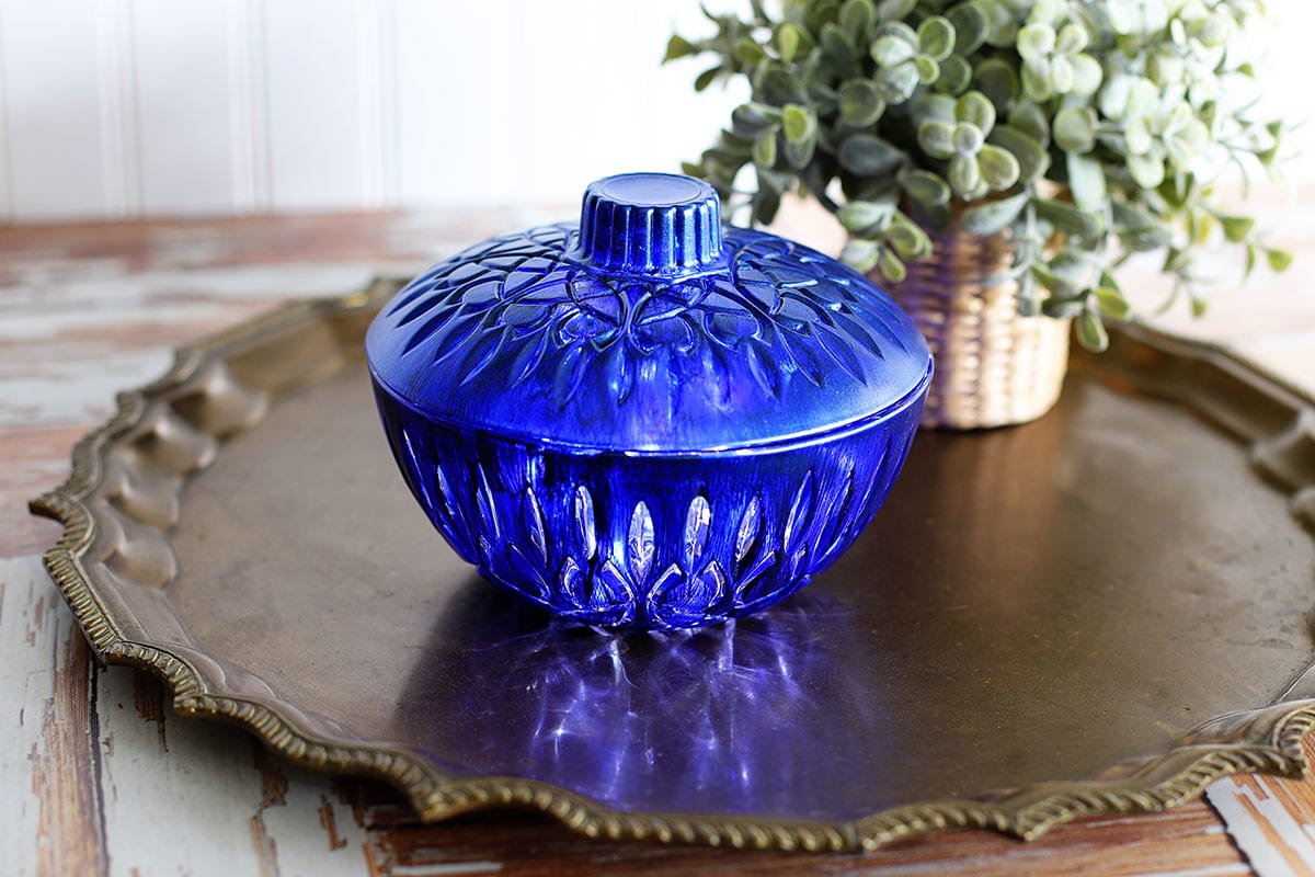 Blue glass candy dish setting on a bronze serving tray.