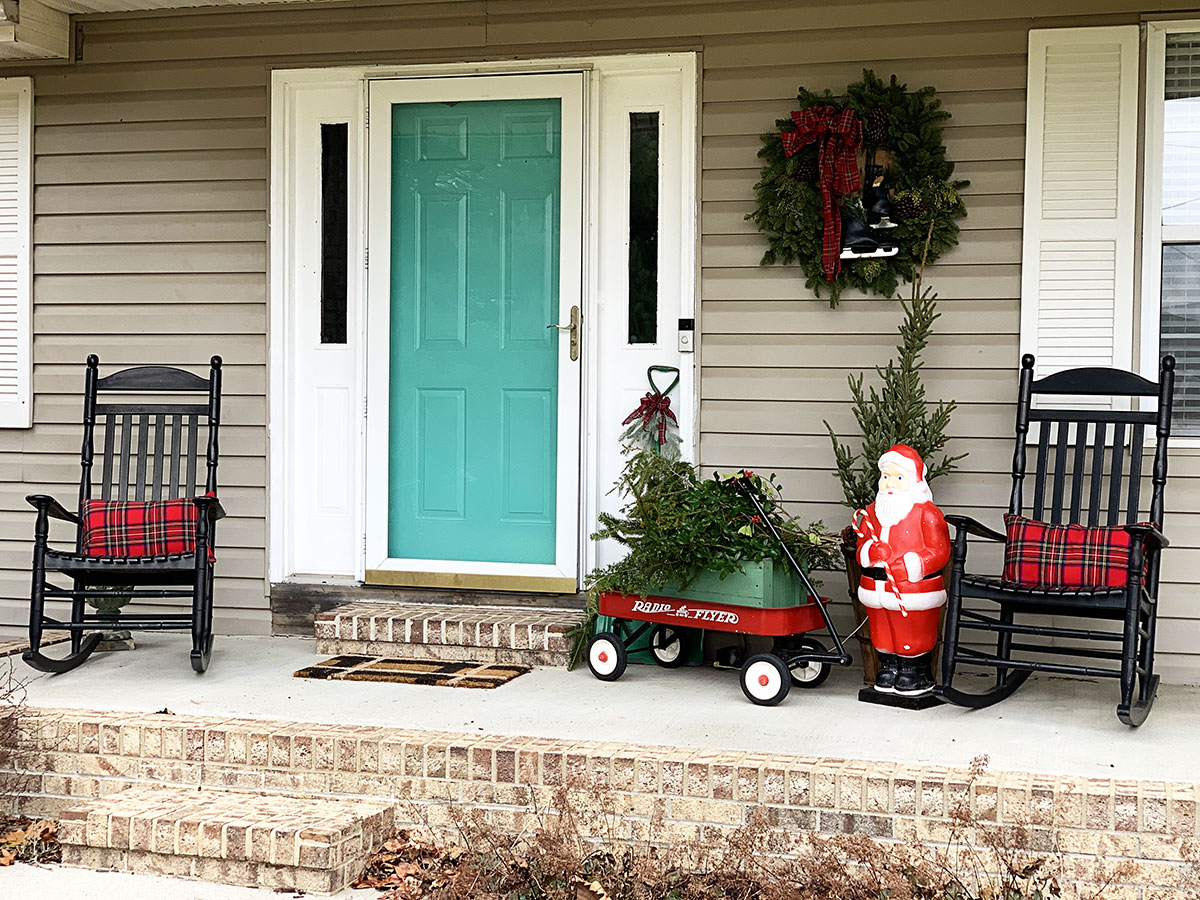 Minimal porch decorations for Christmas including a 1950's blow mold, rocking chairs and a Radio Flyer red wagon.