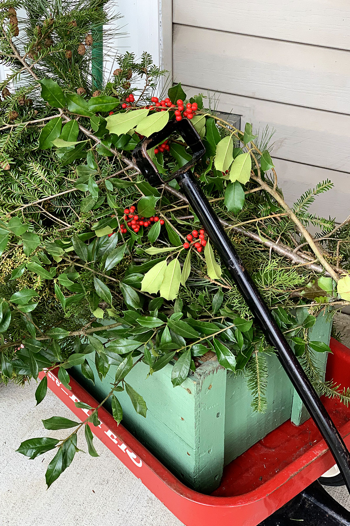 A Radio Flyer red wagon used as decoration on a Christmas porch. 