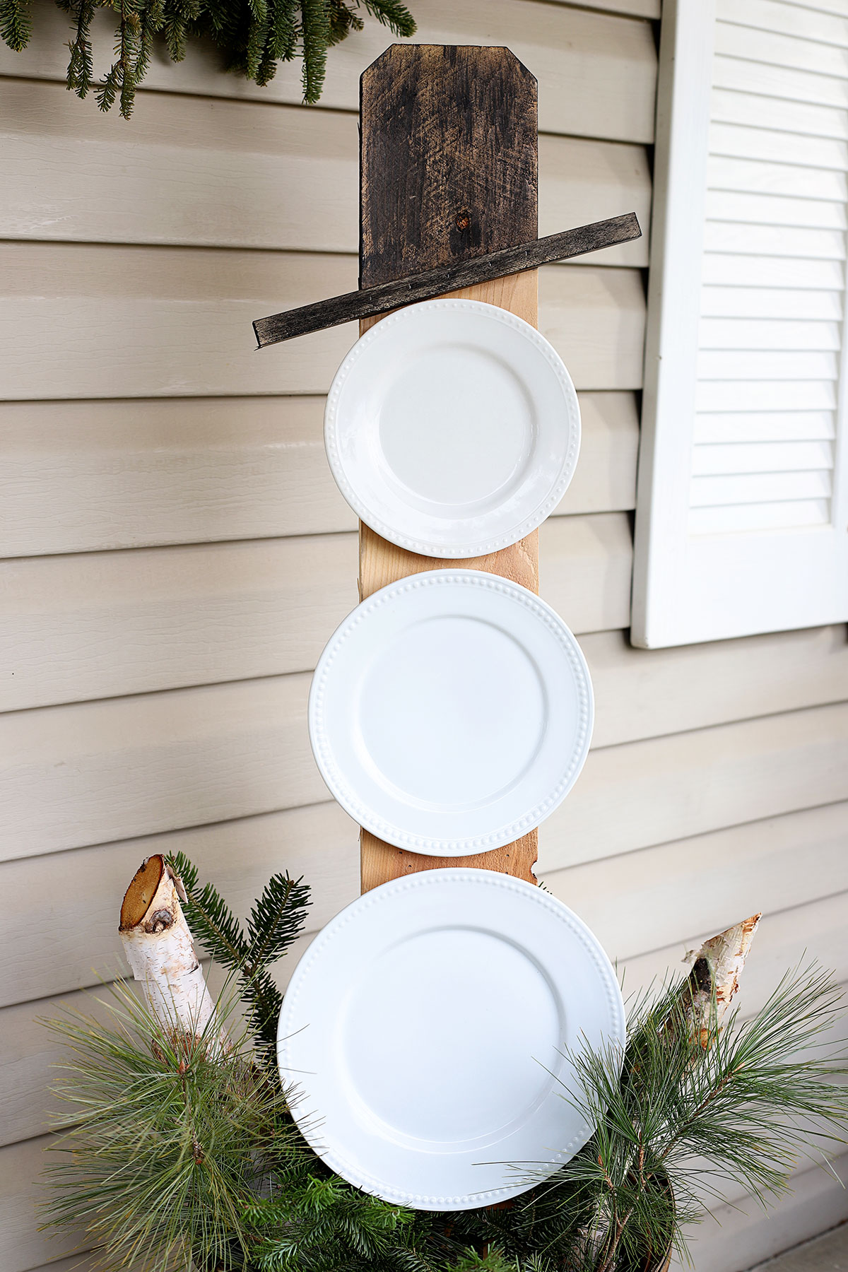 Snowman made from repurposed white plates. Used as porch decor for after Christmas.