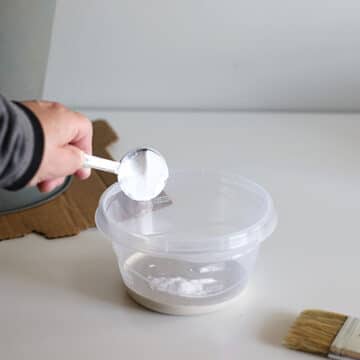 Pouring baking soda into paint to create a textured paint.